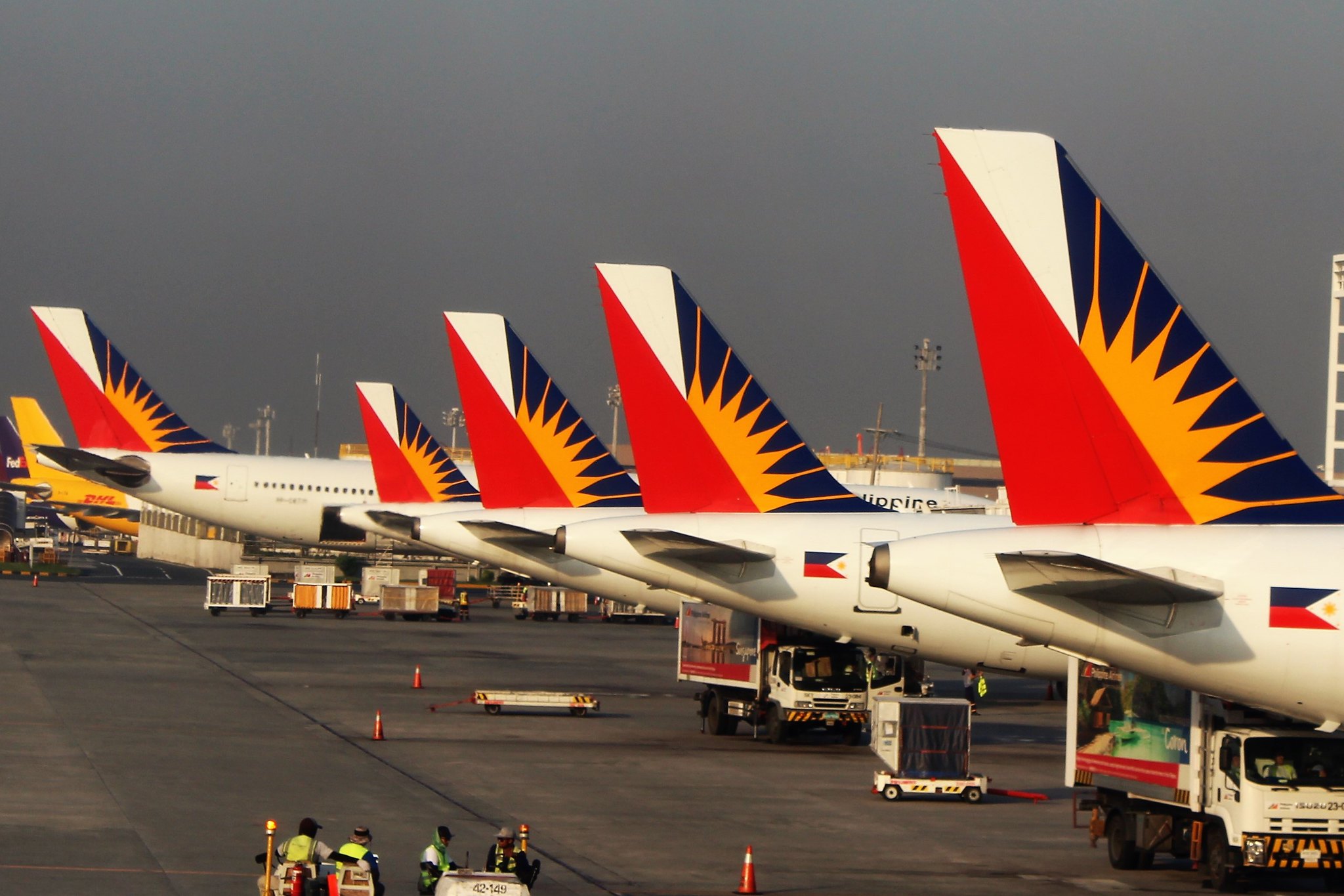 Philippine Airline planes all lined up along the tarmac.