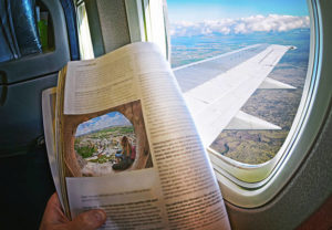 Woman Is Sitting By Window On A Plane With an inflight magazine