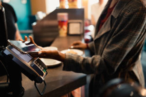 Close-up of a woman using their smart phone to pay by contactless.