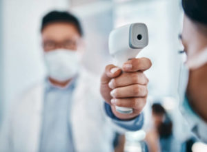 Shot of a young woman getting her temperature taken with an infrared thermometer by a healthcare worker during an outbreak