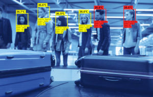 Facial recognition system at the airport during covid-19 pandemic, measuring temperature. People waiting for luggage.