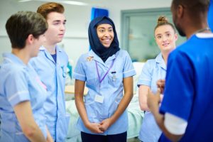 four young medical staff members chat to each other and their manager after a shift on the wards.