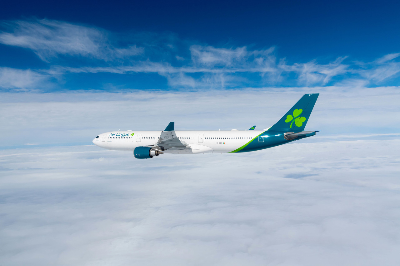 Aer Lingus Airbus A330-300 plane shown flying above the clouds against a blue sky.