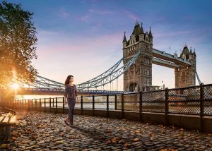 A cinematic shot: The Singapore Girl walking along London's Tower Bridge