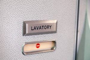 Vacant red sign, occupied symbol on an airplane lavatory door. Raised, brushed metal lavatory sign, recessed plastic vacant sign. Toilet room, wc, water closet on airplane board