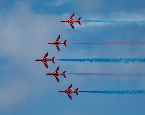The Red Arrows flying in unison at an air show display leaving a trail of red, white and blue