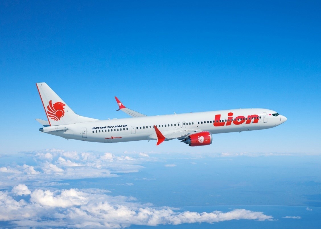 Image shows a red and white Lion Boeing 737 MAX aircraft in a blue sky with white clouds below