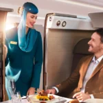Oman Air Hostess tending to Business Studio passenger with gourmet a la carte fine dining