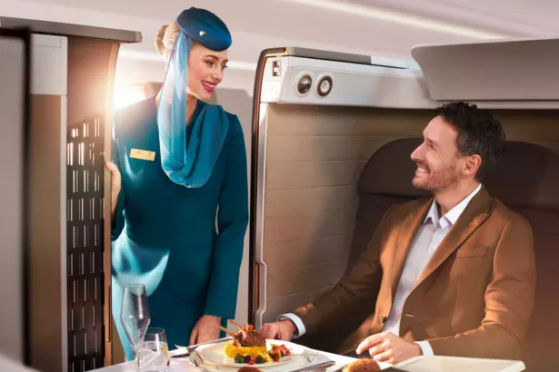 Oman Air Hostess tending to Business Studio passenger with gourmet a la carte fine dining