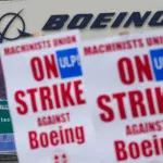 Strikers hold picket signs in front of Boeing's factory in Everett