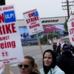 Boeing workers wave picket signs as they strike on September 15, near the company's factory