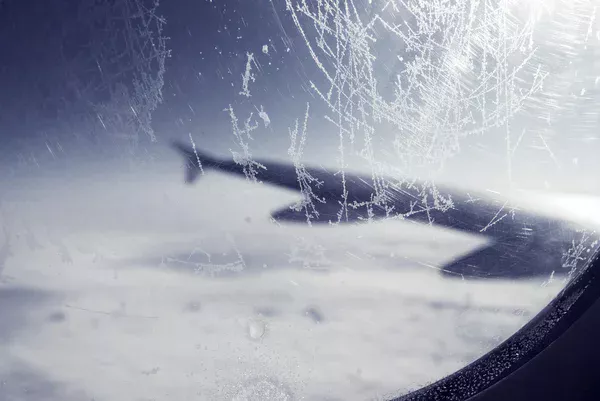 The image of a plane flying during icy and snowy conditions.