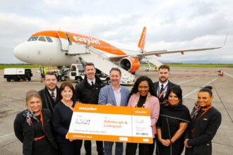 A group of people hold a large cheque outside a plane