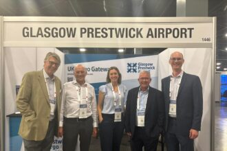 5 people stand below a sign saying Glasgow Prestwick Airport