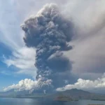 A big and tall grey mushroom of smoke fills the air of Flores