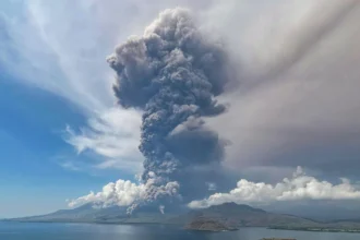 A big and tall grey mushroom of smoke fills the air of Flores