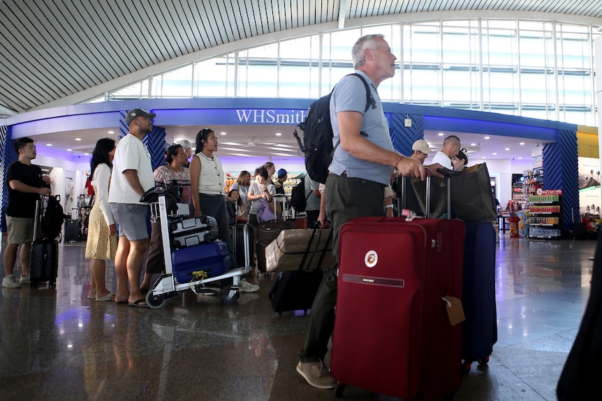 Multiple passengers wait around in I Gusti Ngurah Rai International Airport for updates on their flight © AP Photo/Firdia Lisnawati