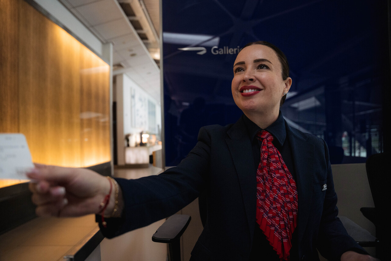 British Airways female staff handing a boarding pass to someone outside the photo. 