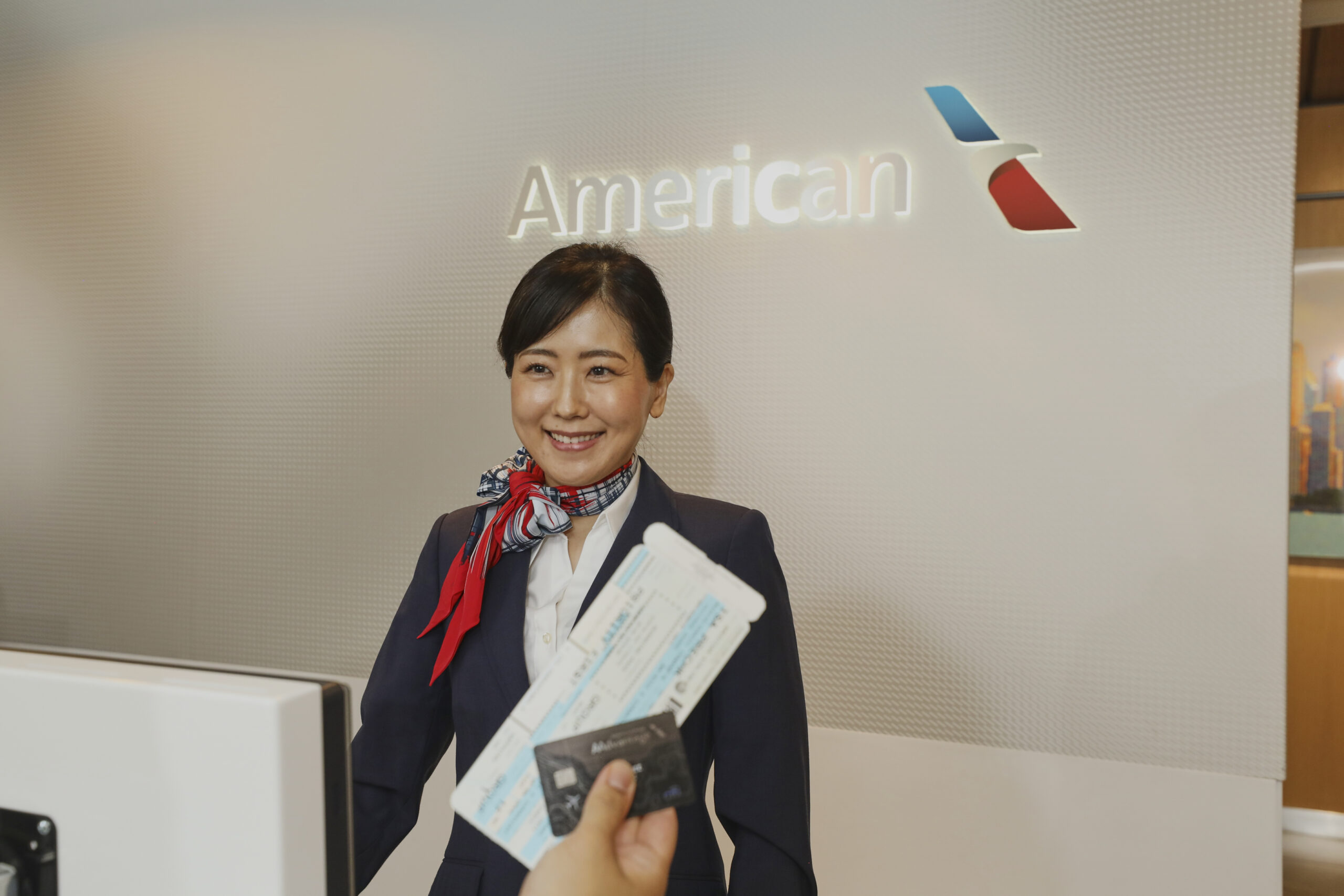 An American Airlines female staff smiling at a customer who is not in the photo