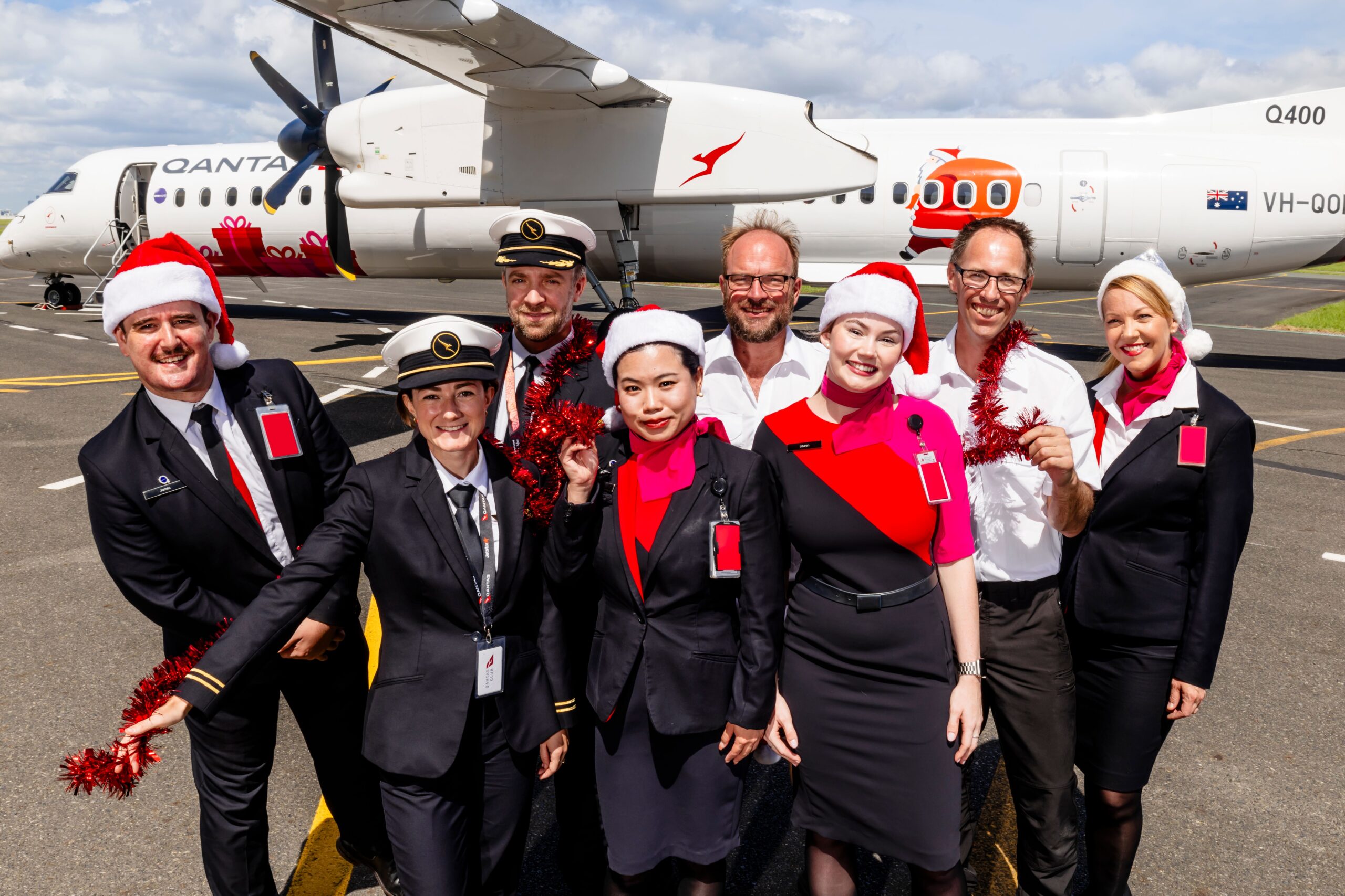 Qantas staff celebrate in front of Qantas Christmas livery