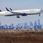 A Boeing 767 passenger aircraft of Delta airlines arrives from Dublin at JFK International Airport in New York as the Manhattan skyline looms in the background on February 7, 2024.
