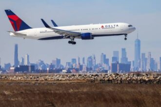 A Boeing 767 passenger aircraft of Delta airlines arrives from Dublin at JFK International Airport in New York as the Manhattan skyline looms in the background on February 7, 2024.