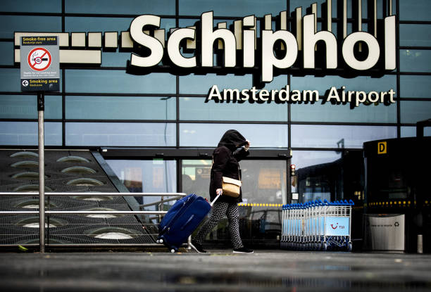 A woman carries a suitcase outside Schiphol Airport