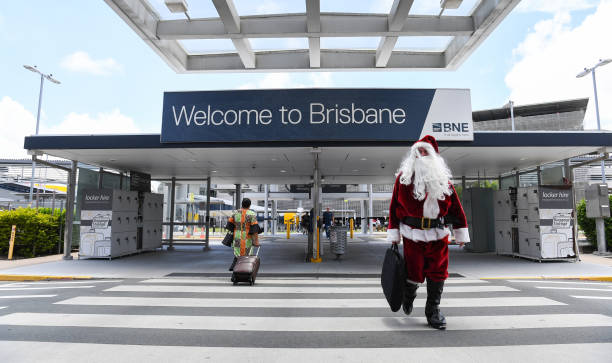 Santa walking across a zebra crossing in front of a welcome to Brisbane sign at Brisbane aiport
