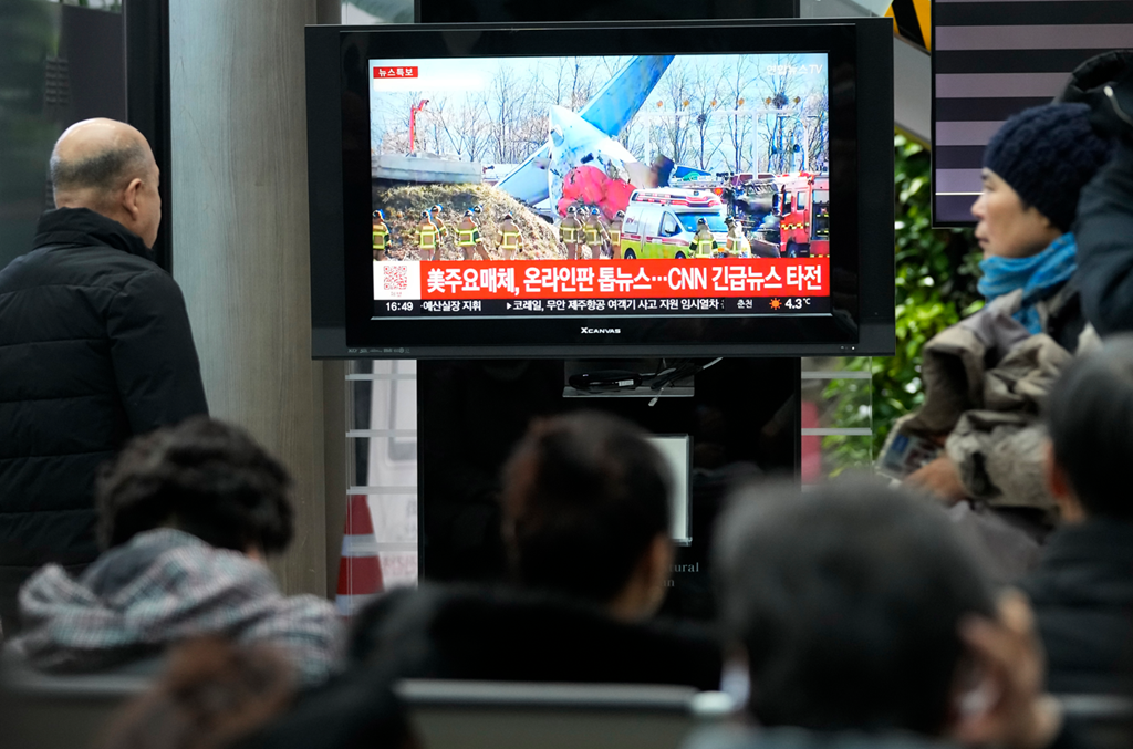 Relatives of passengers watch news about the Jeju Air crash at Muan International Airport.