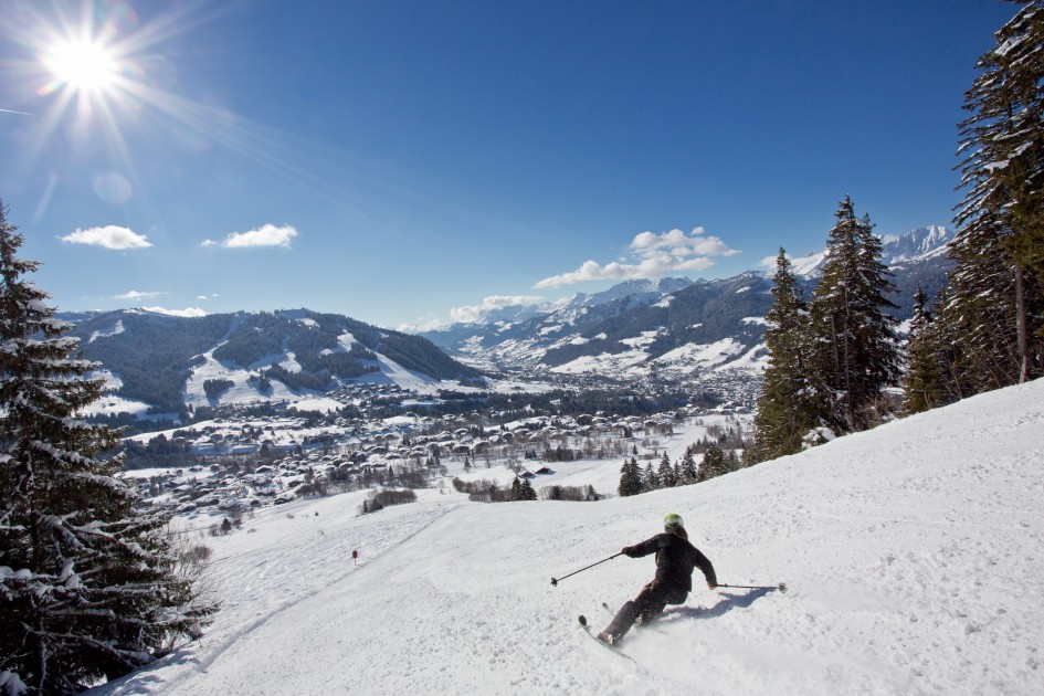 A man skiing on a tall, snowy mountain in beautiful sun