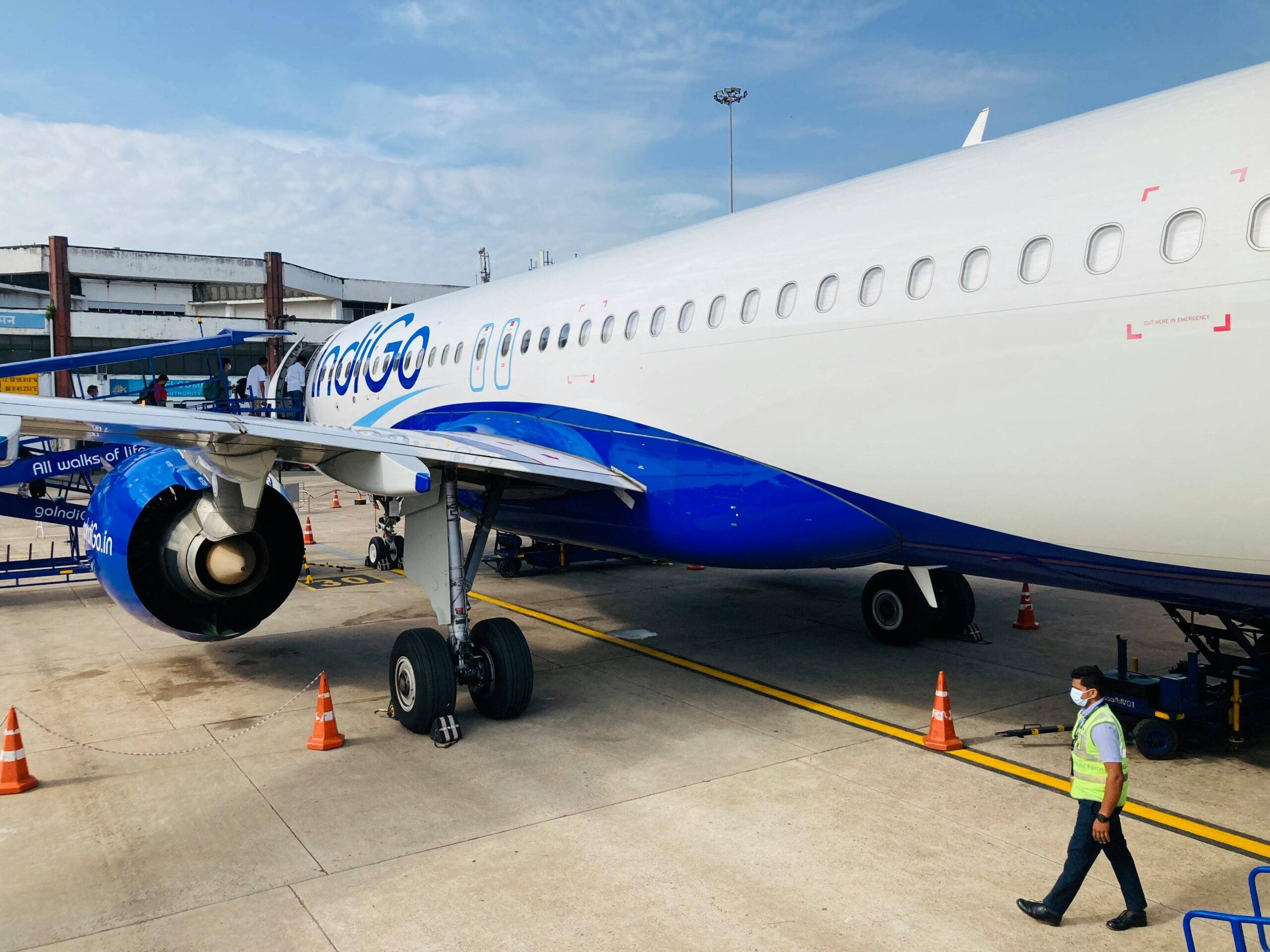 The white and blue livery of IndiGo airlines as it waits for passengers to board