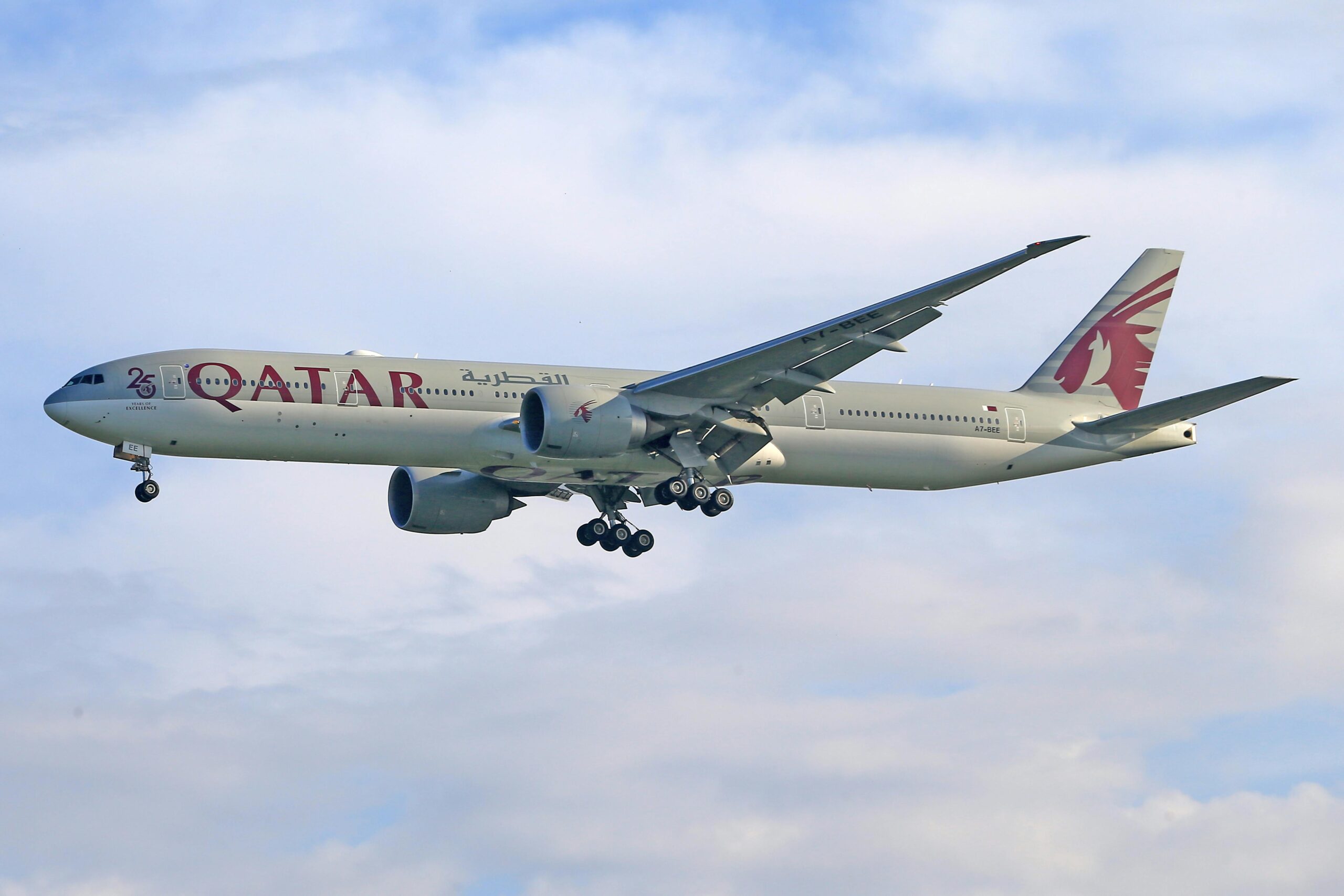 A Qatar Airways plane flying in the sky. 