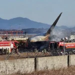 Wreckage of the Jeju Air flight crash at Muan International Airport with emergency responders on site.