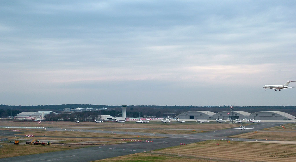 Panorama of Farnborough Airport, Hampshire View from 4th floor suite in 'The Aviator' hotel: Farnborough Airport control tower, hangars. A business jet is just landing.
