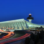 Picture of Washington Dulles International Airport at Dusk, showing the main terminal with lights of speeding cars passing by.