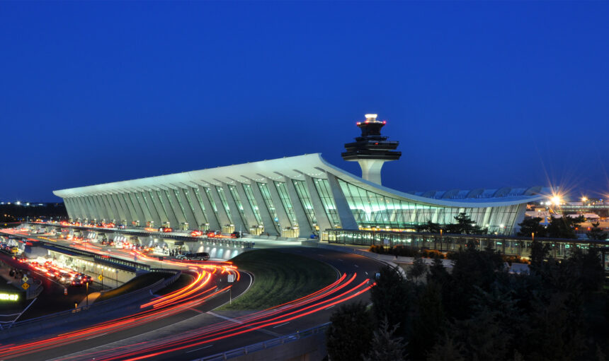 Picture of Washington Dulles International Airport at Dusk, showing the main terminal with lights of speeding cars passing by.