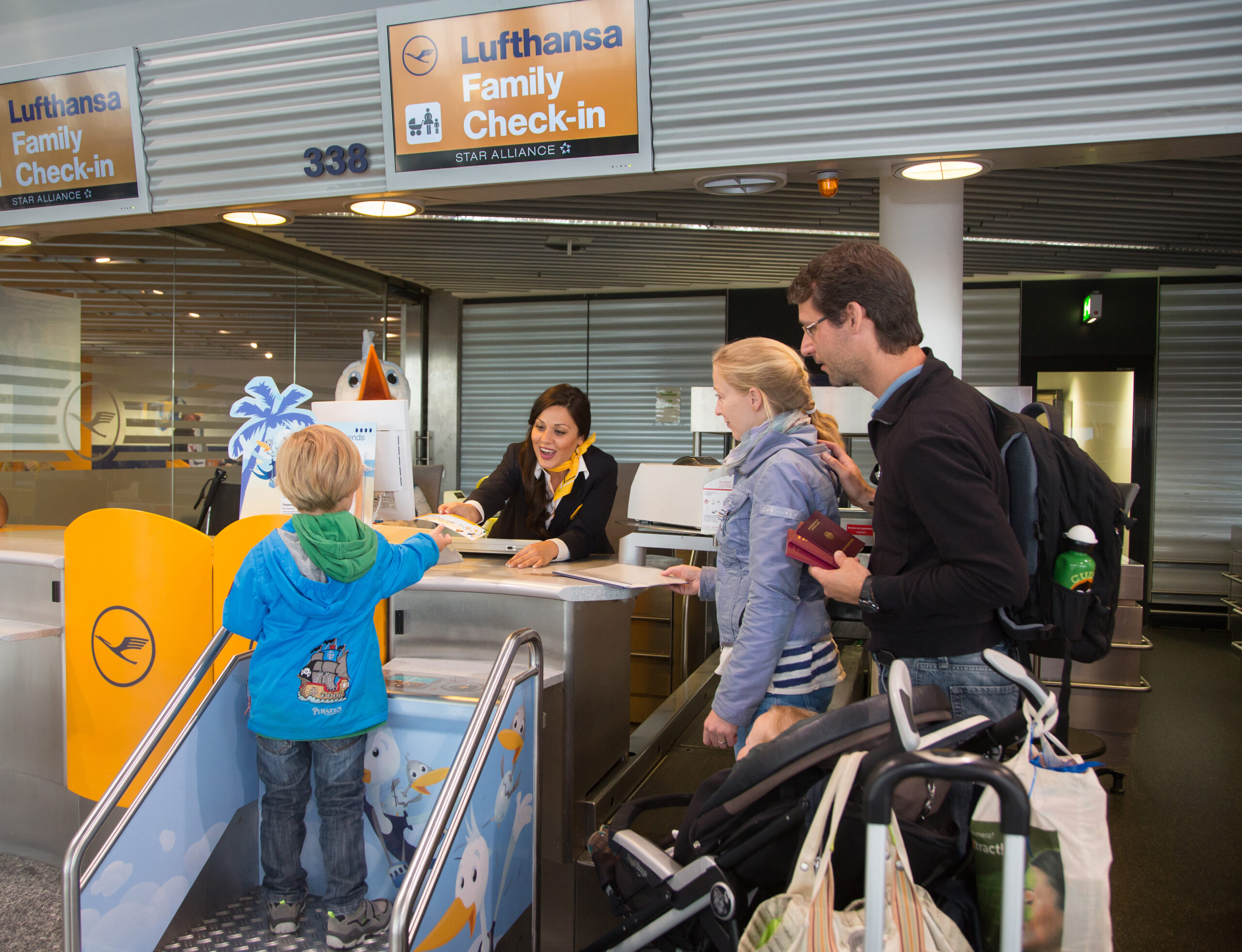 A family checks in to their flight at the airport at a Lufthansa check-in desk.