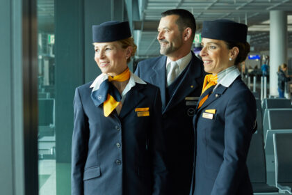 Lufthansa Group airlines staff smile and look out the window in an airport.