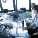 Female petty officers work at their stations in an air traffic control tower.