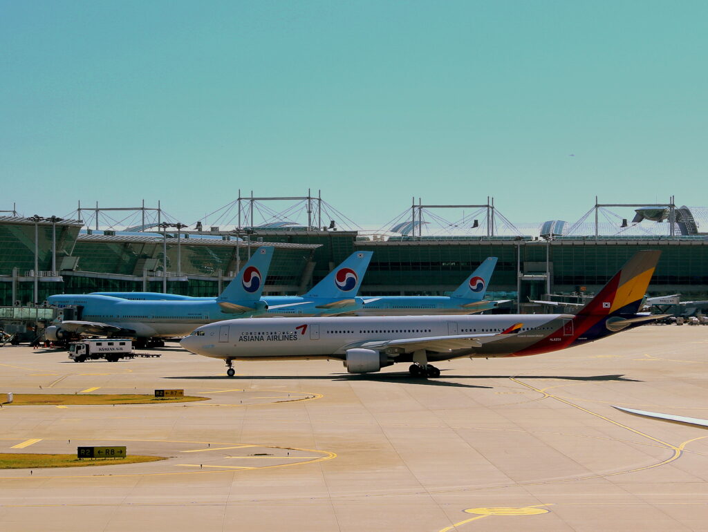 An Asiana Airbus A330-300 at Incheon International Airport with other Korean Air aircraft behind it.