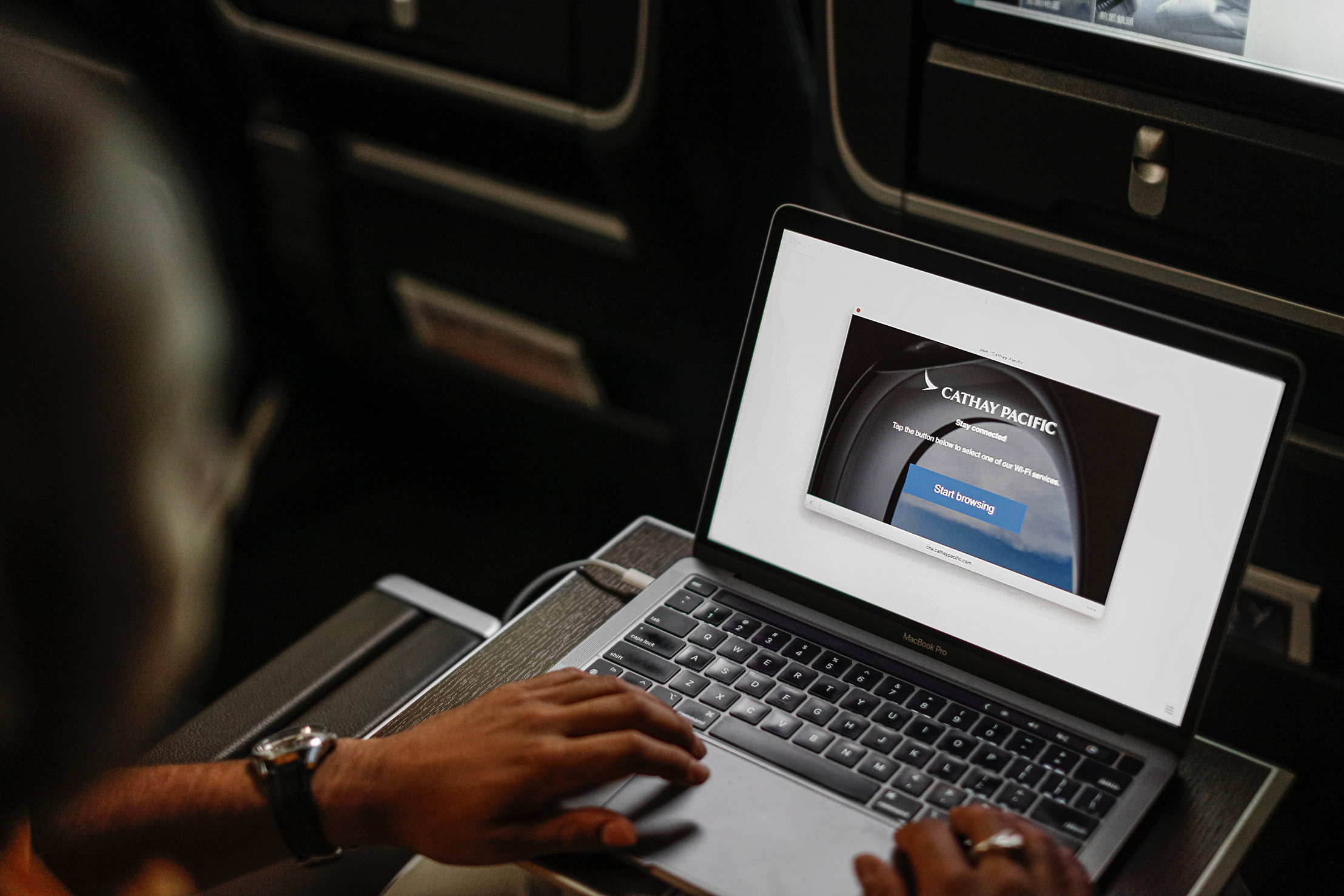 A passenger using a MacBook Pro on a Cathay Pacific flight, accessing the airline’s in-flight Wi-Fi portal.