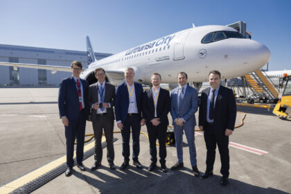 A group of airline and industry executives posing in front of a Lufthansa City Airlines Airbus A320neo on the airport tarmac during a delivery event.