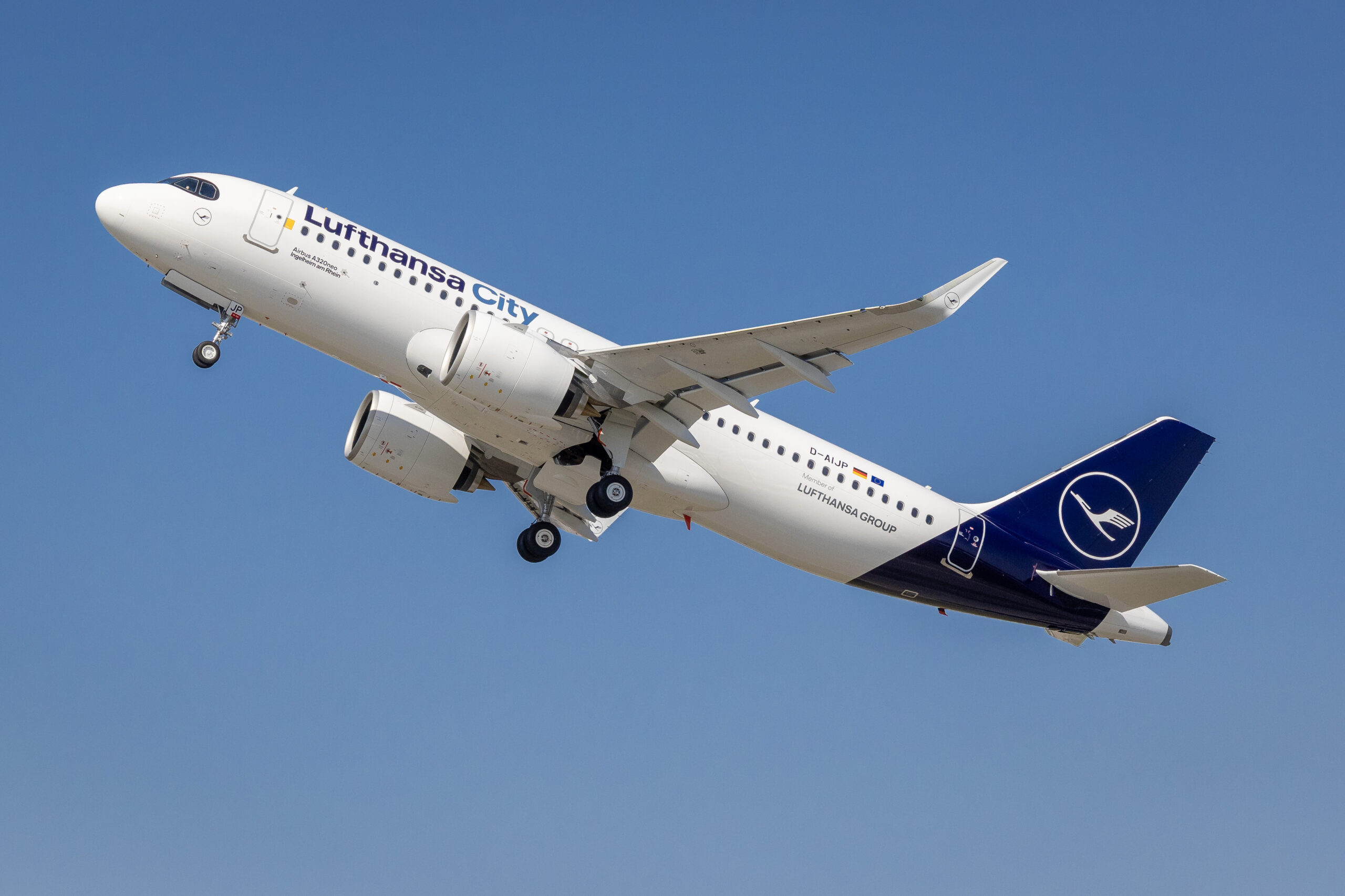 A Lufthansa City Airlines Airbus A320neo lifting off during takeoff, with gear extended against a bright blue sky.