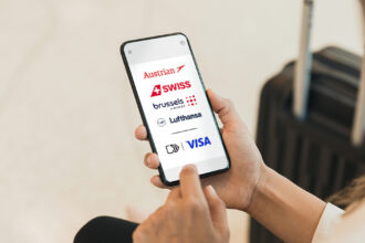 A person holding a smart phone. The screen showing the logos of Lufthansa Group airlines, including Lufthansa, SWISS, Austrian Airlines, and Brussels Airlines. © Lufthansa Group