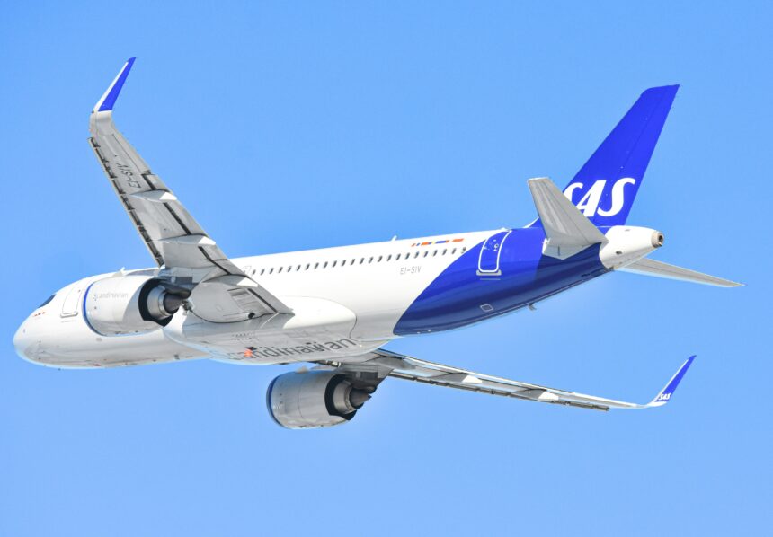 A Scandinavian Airlines (SAS) Airbus aircraft with a blue and white livery is soaring through a clear blue sky.