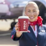 A member of Jet2 crew proudly displays a cup of Costa Coffee.