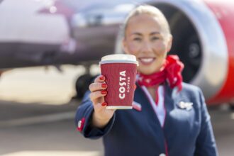 A member of Jet2 crew proudly displays a cup of Costa Coffee.