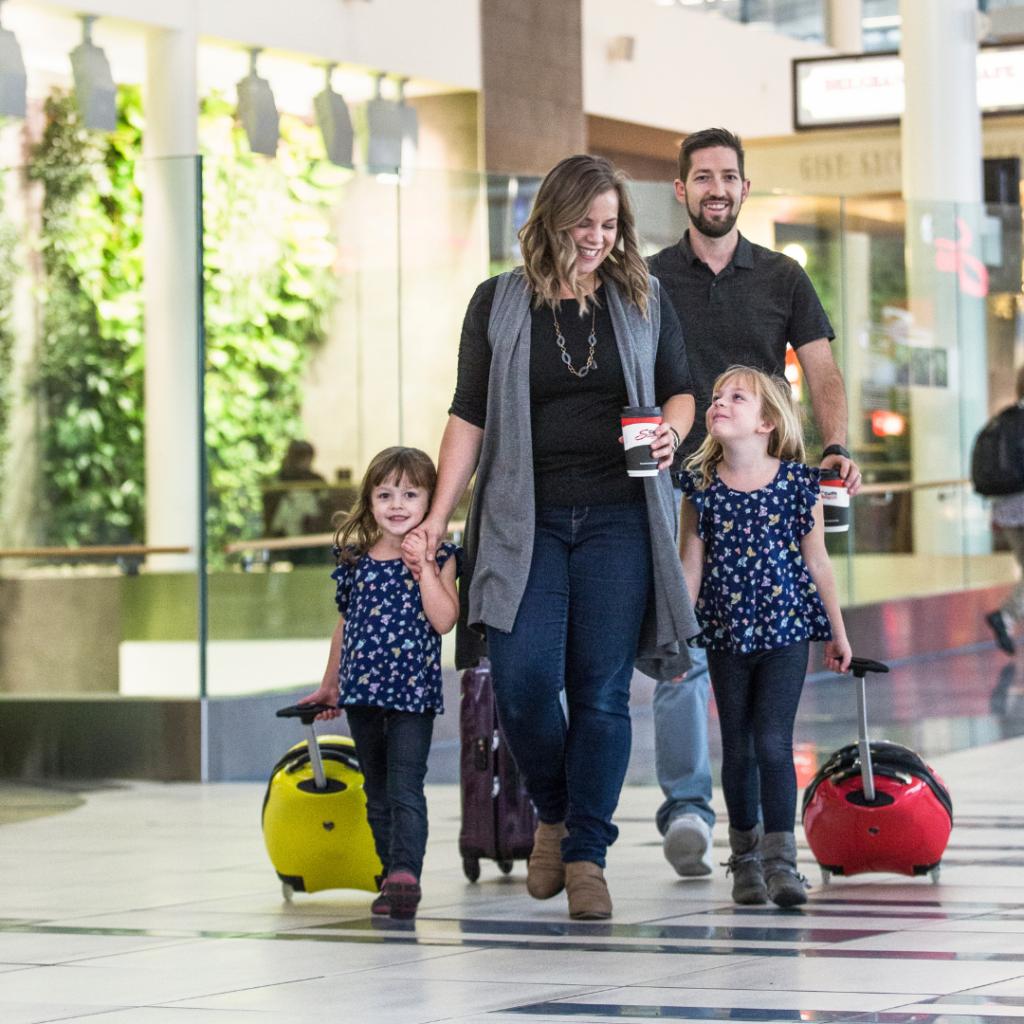 A family walk through the airport with their luggage.