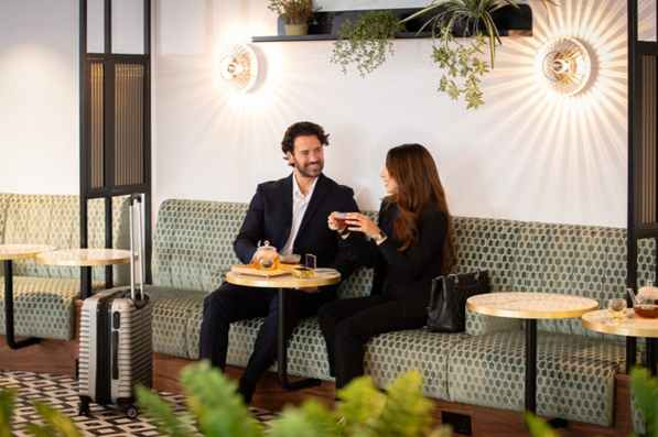 Two passengers enjoy tea on a lounge bench.