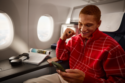 A passenger smiles as he orders on his phone onboard an aircraft.